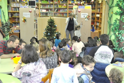 Un momento del cuentacuentos en la sala abarrotada de niños y niñas, mamás y papás. 