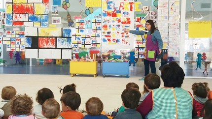 La educadora de la escuela infantil de El Chaparral junto a las pinturas de los pequeños.