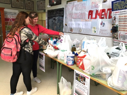 Varias alumnas hacen su aportación solidaria en la mesa instalada en el hall del IES Aricel.