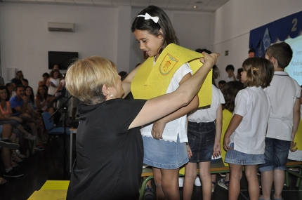 Una pequeña recibe la banda de graduación durante el acto. 