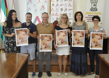 La concejala de Comercio y Consumo, con representantes de ASCOAL y varios comerciantes locales muestran el cartel de la pasarela tras la rueda de prensa. 