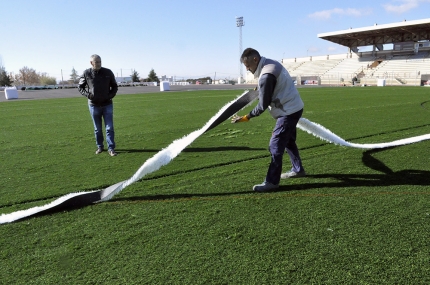 El concejal visita las obras mientras un operario se prepara para colocar la línea frontal de una de las área de juego.  