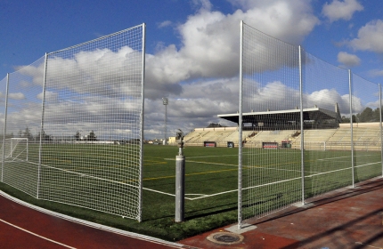 Imagen en la que se aprecia el césped nuevo, el vallado del perímetro de juego y uno de los cañones de riego. 