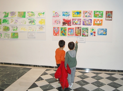 Dos pequeños participantes observan sus dibujos colgados en la sala de exposiciones de la Casa de la Cultura.