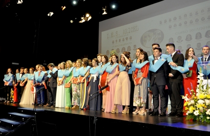 Alumnado al final del acto saluda en el borde del escenario con sus bandas celestes. 