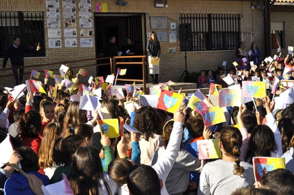 Los escolares agitan la nueva bandera del colegio Tínar durante la interpretación de los himnos nacional y andaluz al inicio del acto grupal en el patio del colegio 