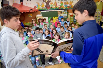 Alumnos del IES Aricel muestran un libro a los infantiles del cole Abadía. 