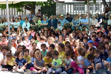 Alumnado del centro en primer término y autoridades, invitados y profesorado detrás, durante el desarrollo del acto en el patio del colegio. 