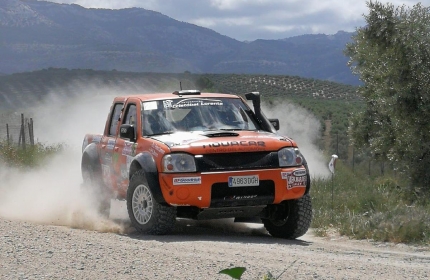 El Nissan Navara D22 del equipo MC Rally Offroad por una de las pistas del trazado con el mar de olivos de fondo. 