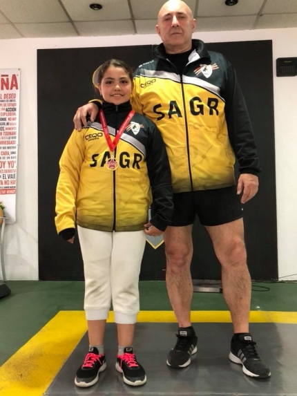 Julia Nerea luce su medalla de oro junto a su maestro de esgrima Manuel Cañadillas en las instalaciones del club Sala de Armas de Granada/ SAGR