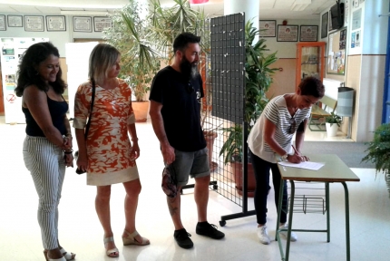 Varias madres y padres firman en la mesa instalada en el hall del IES Aricel. 